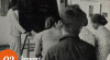Foto suasana belajar di dalam kelas yang diikuti oleh sekelompok pemuda dan pemudi, dengan seorang guru perempuan berdiri di samping papan tulis. 2 Januari 1952.